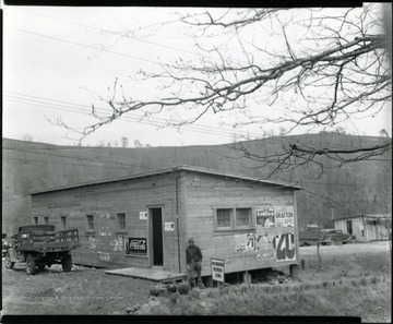 Man leading against outside of old, wooden store in Grafton, W. Va.