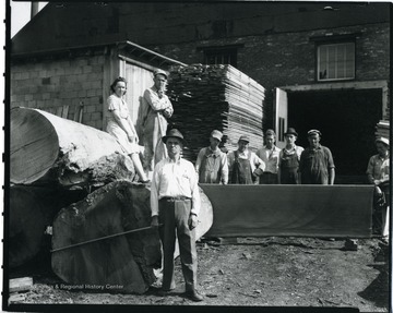 Woodyard family members and employees outside at the lumber yard on West Main Street in Grafton, West Virginia. Left to right: W. A. Woodyard, owner of the company (holding a measuring stick) and father; Bertha Woodyard-daughter; Ralph Woodyard-son; Clair Woodyard-son; Unidentified employee; Bill Woodyard-son; Norman Woodyard-son; Unidentified employee; Unidentified employee.