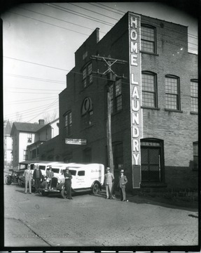 Employees stnad next to trucks at the Home Laundry in Grafton, West Virginia.