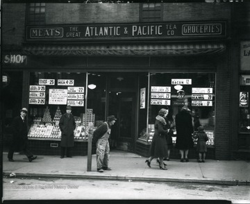 Outside of the Great Atlantic and Pacific Tea Company Groceries in Grafton, W. Va.  Bypassers looking in the window displays.