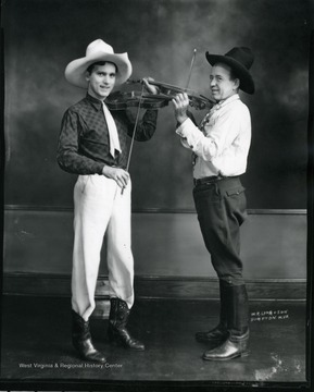 Two men wearing cowboy hats and holding violins.