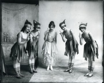 Five female performers dressed in dance costumes pose for a portrait.
