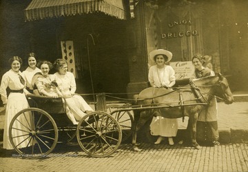 Two women sitting in a horse-drawn carriage, two standing with the horse, and two standing behind the carriage.  Grafton, W. Va.