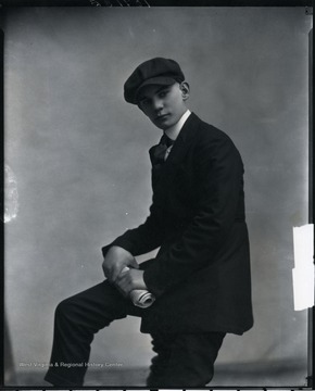 A young man with a newspaper poses for a portrait.