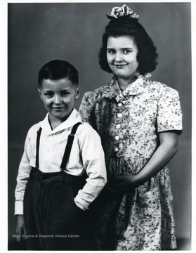 A young boy poses with an older girl in this photograph.