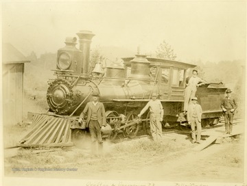 Train engine and "Billey" Grayham, Cap. Jas Flanagan, "Berney" Wilmoth, Jake Blocker, Agt. standing around the locomotive.