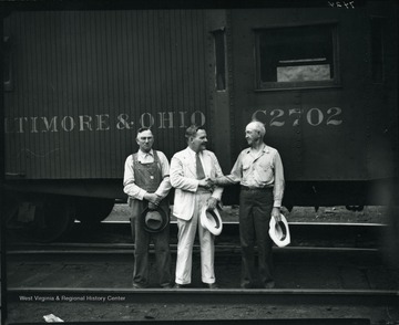 Three Baltimore and Ohio workers standing in front of a B and O train engine, Grafton, W. Va.
