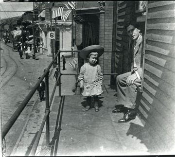 Man with a small child on a balcony overlooking Main Street in Grafton, W. Va.
