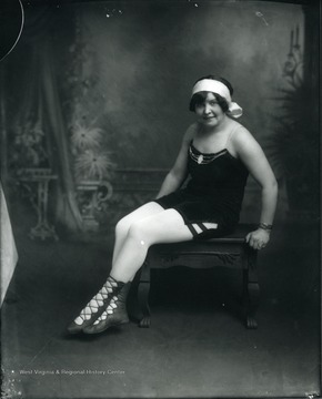 A woman performer is sitting on a stool.