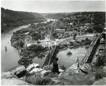 Man and woman sitting on a hillside overlooking bridges in Harpers Ferry, W. Va.
