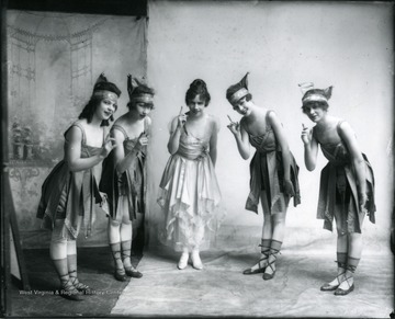 Five dancers gesture to the camera.