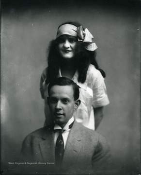 Portrait of a young lady standing behind a young man.