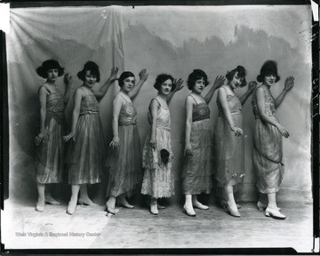 Seven female performers are standing in a line.