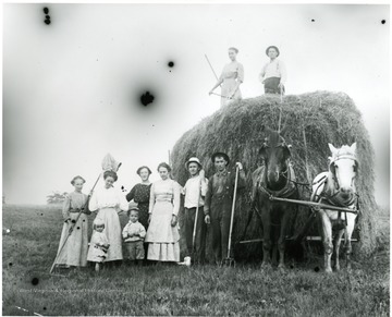 The Aegerter Family standing beside two horses pulling a large bale of hay.  Helvetia, W. Va.