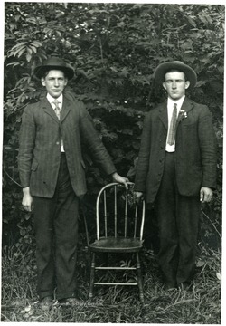 Two young men standing by a chair.  'Paul A from one Fred Burky.'
