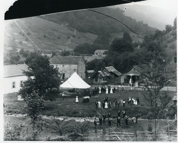 Inscribed on the back, "Showing the Star Band, horse-drawn 'swing' (merry-go-round), homes (l-r) Gottlief Datwlyer, cobbler shop, community store". 