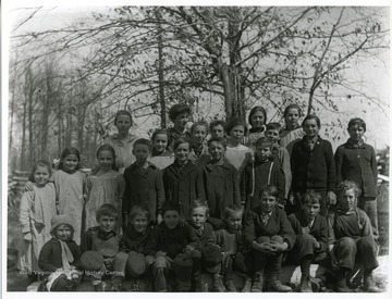 Group portrait of school children and teacher taken outside.