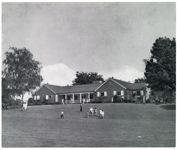 People stand in the grass in front of the Recreation Building at St. Cloud Commons.