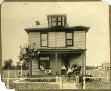 A young man on a bicycle, two girls, and a gentleman have joined Mrs. Gibson on her front porch in order to celebrate her birthday.