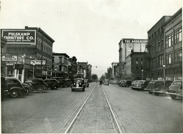 Cars line the streets in Huntington, W. Va.  Model Furniture Company, Wolf Provision Company, sign for Pulskamp Furniture Company visible on left; Huntington Dry Goods Company visible on right.