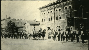 'Fire Department on parade, in front of old city hall, 9th St. between 4th and 5th Ave., where Deardorf Sisler store was located.'