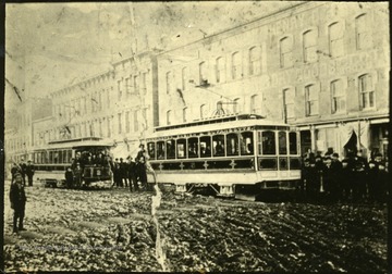 Two of the first electric street cars in Huntington, W. Va going by buildings.  'Huntington's first street car.  Taken with camera looking north and west at the corner of 10th St and 3rd Ave.  This is the second electric street railway in the world.'