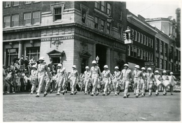 A marching band in uniform goes down the street.