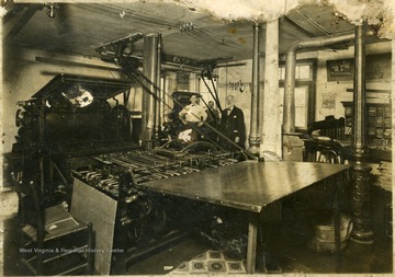 Three men stand beside a large printing machine.