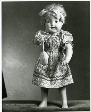 A doll is holding a lollipop in her hand. 