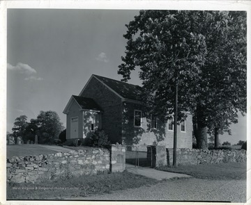 The front of the Tuscarora Church with a tree and a stone fence in Martinsburg, West Virginia.