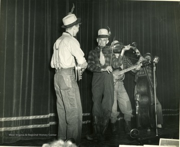 Men are playing instruments including a banjo, fiddle, guitar and a string bass.