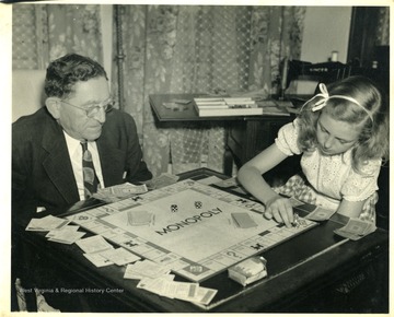 Unidentified man playing monopoly with a young girl.