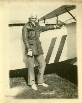 An airplane pilot stands in front of his plane.