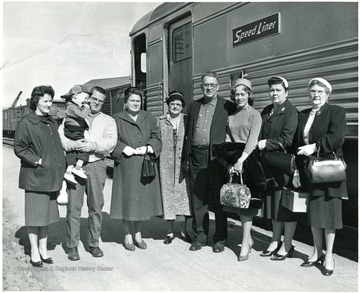 Eight people and one small child (held) standing beside a Speed Liner train car, Martinsburg, W. Va.