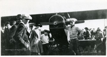 Several people examine a "Jenny" airplane, one of the most widely used models during World War I. This event was likely part of a post-World War I barnstorming tour.