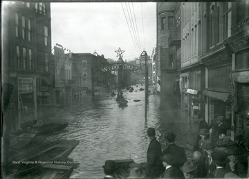 People riding in boats on flooded Market Street under a welcome sign, Parkersburg, W. Va.