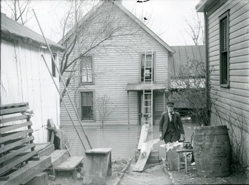 Man walking away from a flooded house.  Entrance to the house gained by a ladder up on the porch, Parkersburg, W. Va.