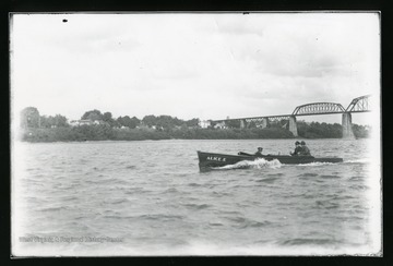 Three men are enjoying a boat ride on a river near a bridge.