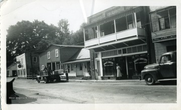 A woman is standing outside Rader's Grocery on a street of an unknown city.