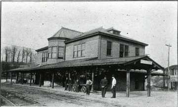 People stand next to the tracks at the passenger depot.