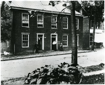 'Dr. Fielding Yost and wife Malanda Ann Yost lived in this house in Morgantown, W. Va.  This is on Main St.  They put three sons through college to be Dr.'s.  Copied from back of picture owned by Lewis Stemple, loaned to Dr. Core for Copying - written Mar. 1978; Is this on the west side of High Street or corner of Wall Street?  Marion Tapp thinks it is the Franks Home, S. W. corner of Fayette St. and University Ave.  She lived near there as a child.  A double home is on the site of the Morgantown plat of 1921.'