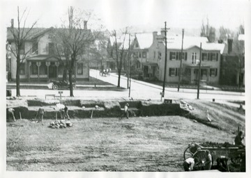 Construction workers are excavating the site for the Morgantown Post Office, at the corner of Kirk and High Streets in Morgantown, West Virginia; Mrs. George C. Sturgiss took this photo from her two-story residence.