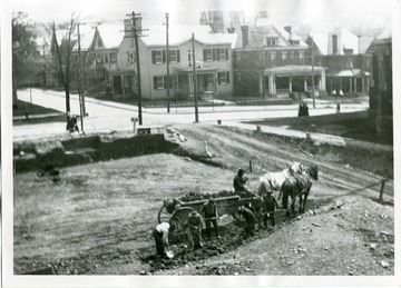 Construction workers are excavating the site for the Morgantown Post Office, at the corner of Kirk and High Streets in Morgantown, West Virginia; Mrs. George C. Sturgiss took this photo from her two-story residence.