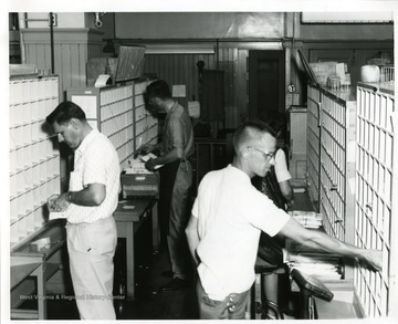 Four postal workers are sorting letters in the interior of the Morgantown Post Office, Morgantown, West Virginia.