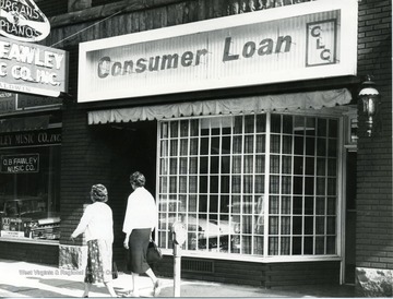 Consumer Loan office located in Morgantown, W. Va. Pedestrians passing by, walking down the street. O.B. Fawley Music Company to the left of Consumer Loan