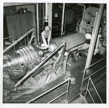 Coal Research Bureau (Bureau of Mines). Charles N. Resenecker of the Bureau's gas turbine staff checks assembly of the bearing between the turbine and compressor rotors. The large bladed rotor at the left contains the new blades, and is the heart of the gas turbine plant. The air compressor is the bladed unit at the right. Hot high-speed gases from the combustion of coal spin the rotor at the left and then leave through an exhaust stack (not shown). The air compresor, rotated by the turbine, supplies air needed to burn the coal. The turbine also drives electric generators (not shown in this photograph).