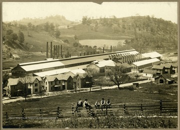 American Sheet and Tin Mill looking South East. Located in Morgantown, W. Va. Men and children sitting on fence located near Mill. Houses located near Mill. 