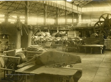 'This picture shows the spare rolls ready to take the place of those constantly in use in the hot mills. This mill uses 50 or 60 of them and they are relieved from duty once a week and sent to a roll turner who redresses each and again makes it ready for duty in some one of the many hot mills where it does another dollars work. One on the extreme right is the barshear which easily cuts the cold steel shown in the upper part of this picture and allows the pieces 15 to 30 inches (in length) to fall at it's side ready for the furnace where they are heated before bringing them into the hot mills. In the lower center the doubling shears are shown.' 