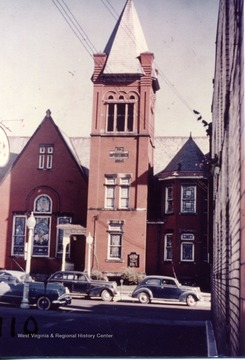 Frontal view of the First Baptist Church located in Morgantown, W. Va. Cars parked at meters in front of Church.