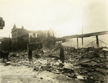 'Strand Theatre fire on High Street in Morgantown', W. Va. Debris from theatre can be seen on street. People standing throughout the debris. Damage from fire seen throughout structures. 